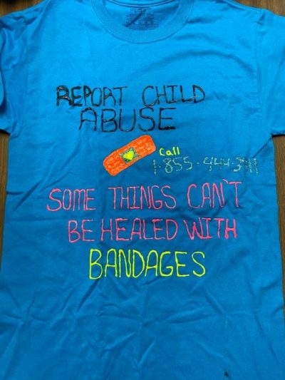 “Report child abuse. Call 1-855-444-3911. Some things can’t be handled with bandages.” Blue represents people who are survivors of incest or child sexual violence.